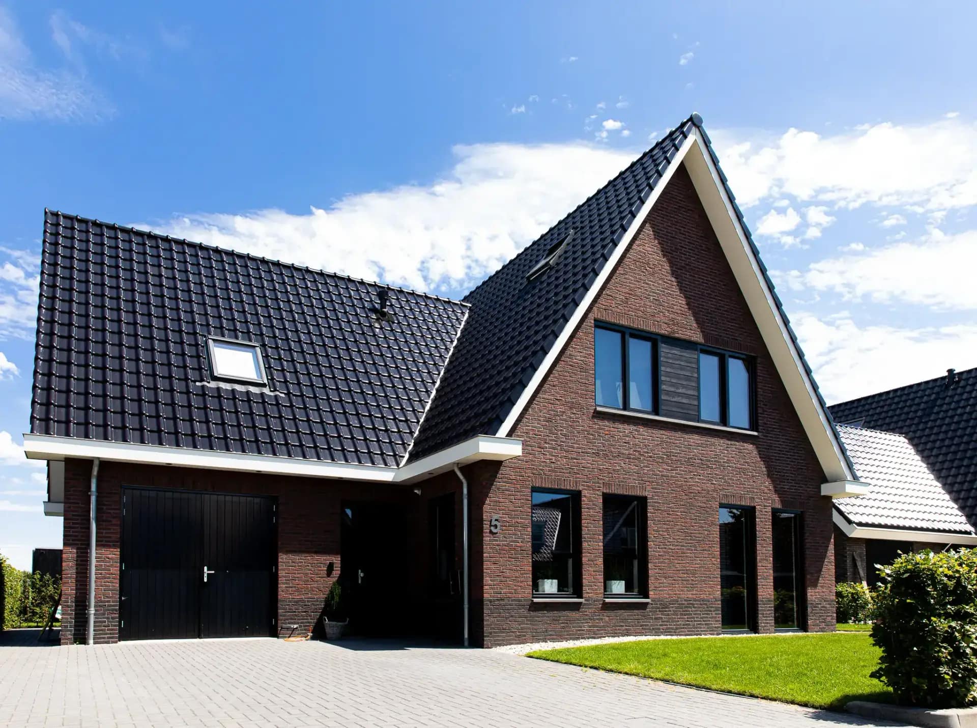 Traditionele T-kapwoning in Wolvega met klassieke materialen, een risaliet aan de tuinzijde en grote glasopeningen met uitzicht op het water.
