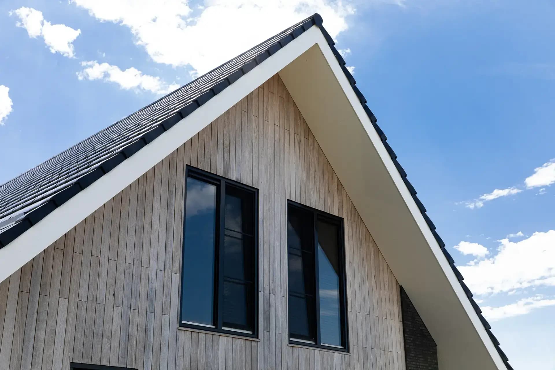 Schuurwoning op een kopkavel aan het Icarusblauwtje in Wolvega, in naturel hout met langformaat metselwerkaccenten en panoramisch uitzicht op het water.