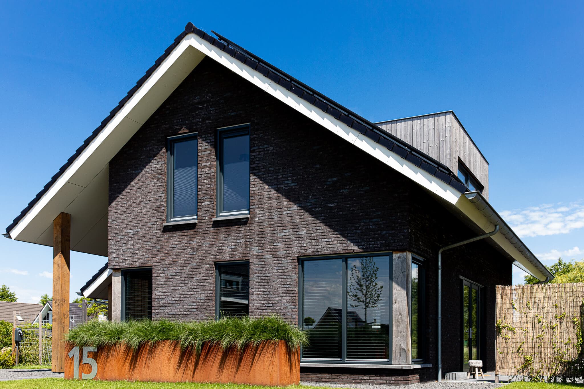 Vrijstaand modern woonhuis aan het Heideblauwtje in Wolvega (Lindewijk) met baksteen, houten accenten, leigrijze kozijnen en licht boeideel.