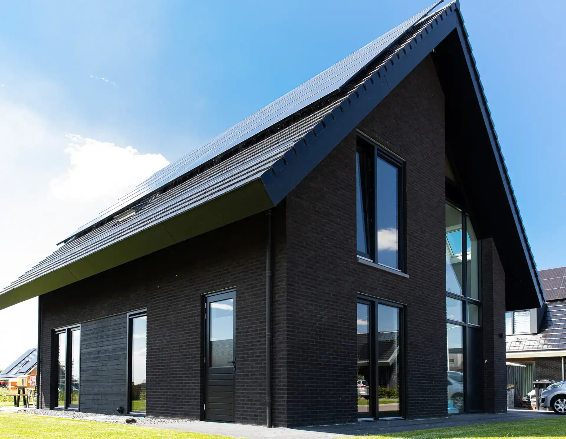 Minimalistisch woonhuis in Wolvega met donkere esthetiek, grote glasoppervlakken, lamellen en houten gevelbekleding in een beperkt kleurenpalet.