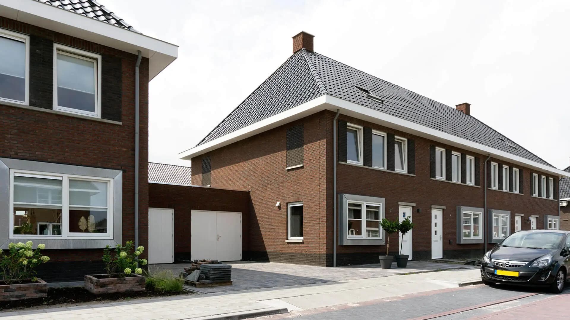 Nieuwbouw van 14 rijwoningen in Wolvega met karakteristieke jaren-dertig architectuur, metselwerk accenten, spekbanden en moderne bloemkozijnen.