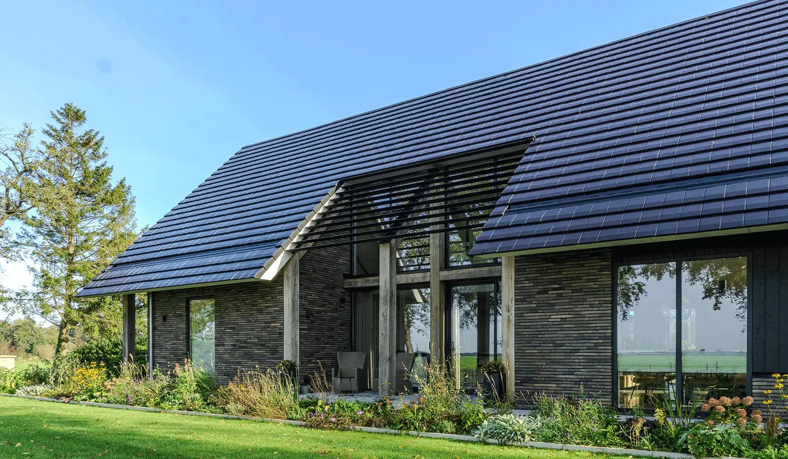 Moderne schuurwoning in Steggerda met open geveltop, houten spanten, donker metselwerk en royale glaspartijen — ontworpen door MArchitecten.