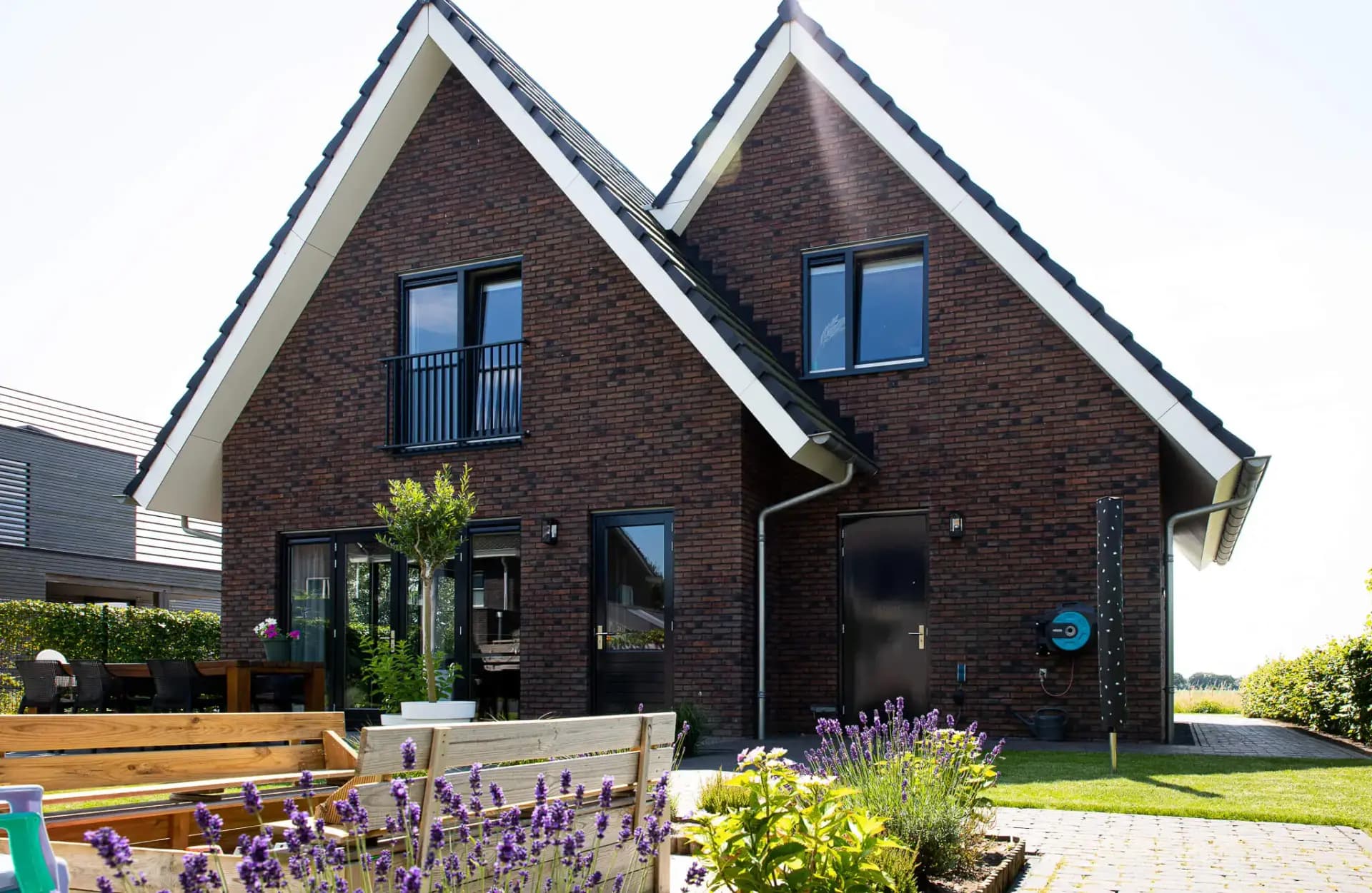 Parallelle kapwoning in Willemsoord met dubbele kapconstructie, twee nokken op één zakgoot, bruinrode baksteen en accenten in naturel hout.