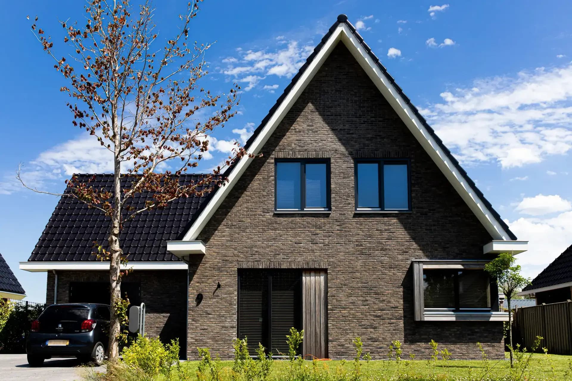 Traditioneel woonhuis Argusvlinder in Wolvega met klassieke gevel, zijbeuk en moderne kleurstelling — grote glaspartijen openen naar uitzicht op het water.