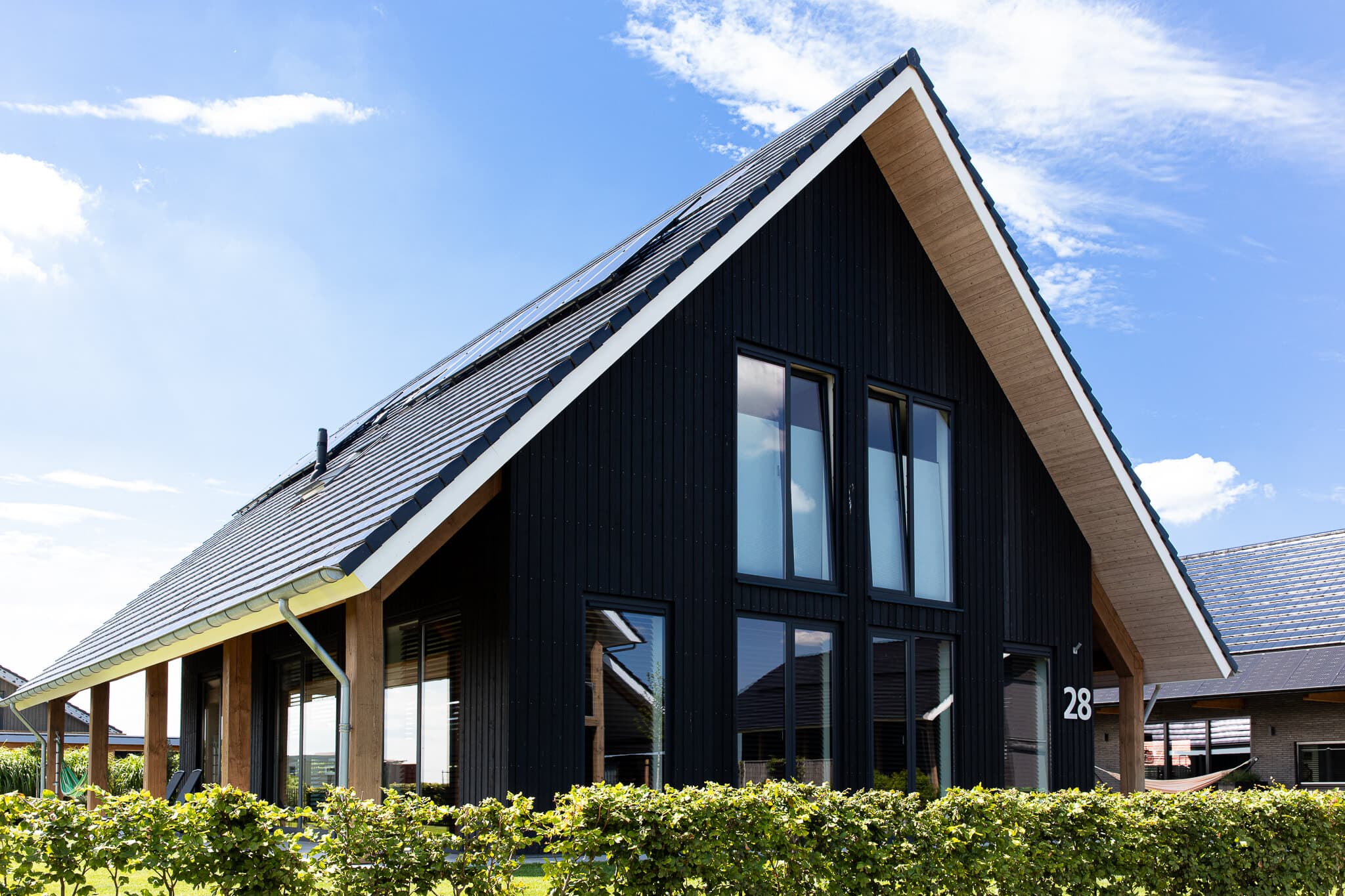 Schuurwoning in Wolvega met zwarte houten gevel, houten spanten en groot dakoverstek aan natuurgebied en water.