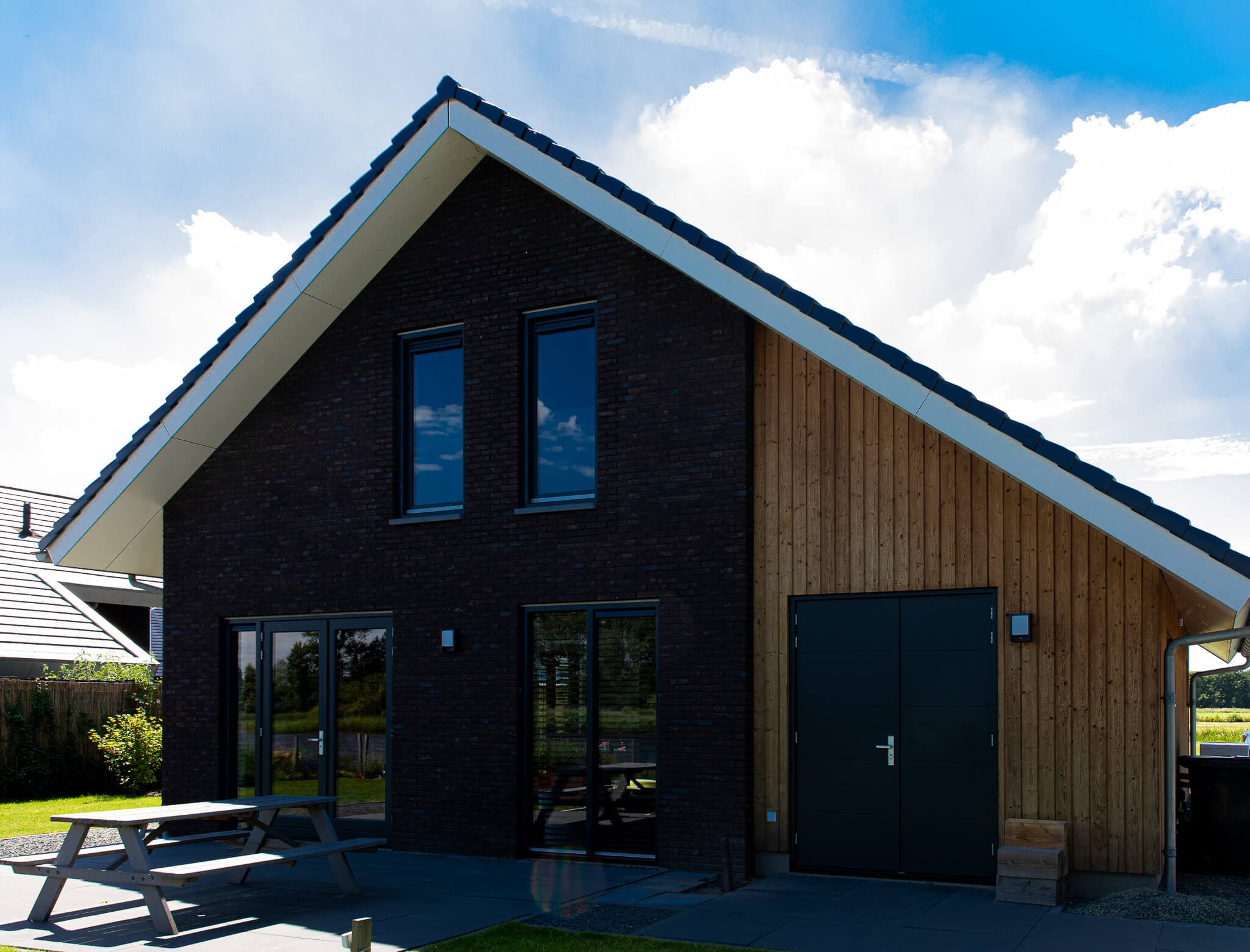 Vrijstaand modern woonhuis aan het Heideblauwtje in Wolvega (Lindewijk) met baksteen, houten accenten, leigrijze kozijnen en licht boeideel.