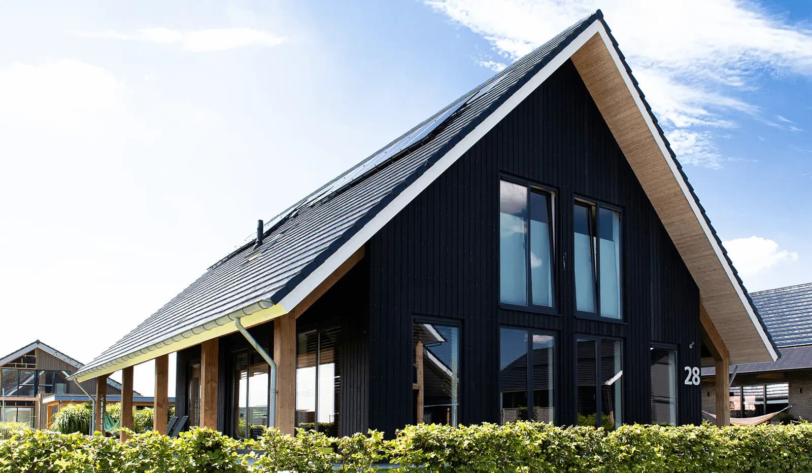 Schuurwoning in Wolvega met zwarte houten gevel, houten spanten en groot dakoverstek aan natuurgebied en water.