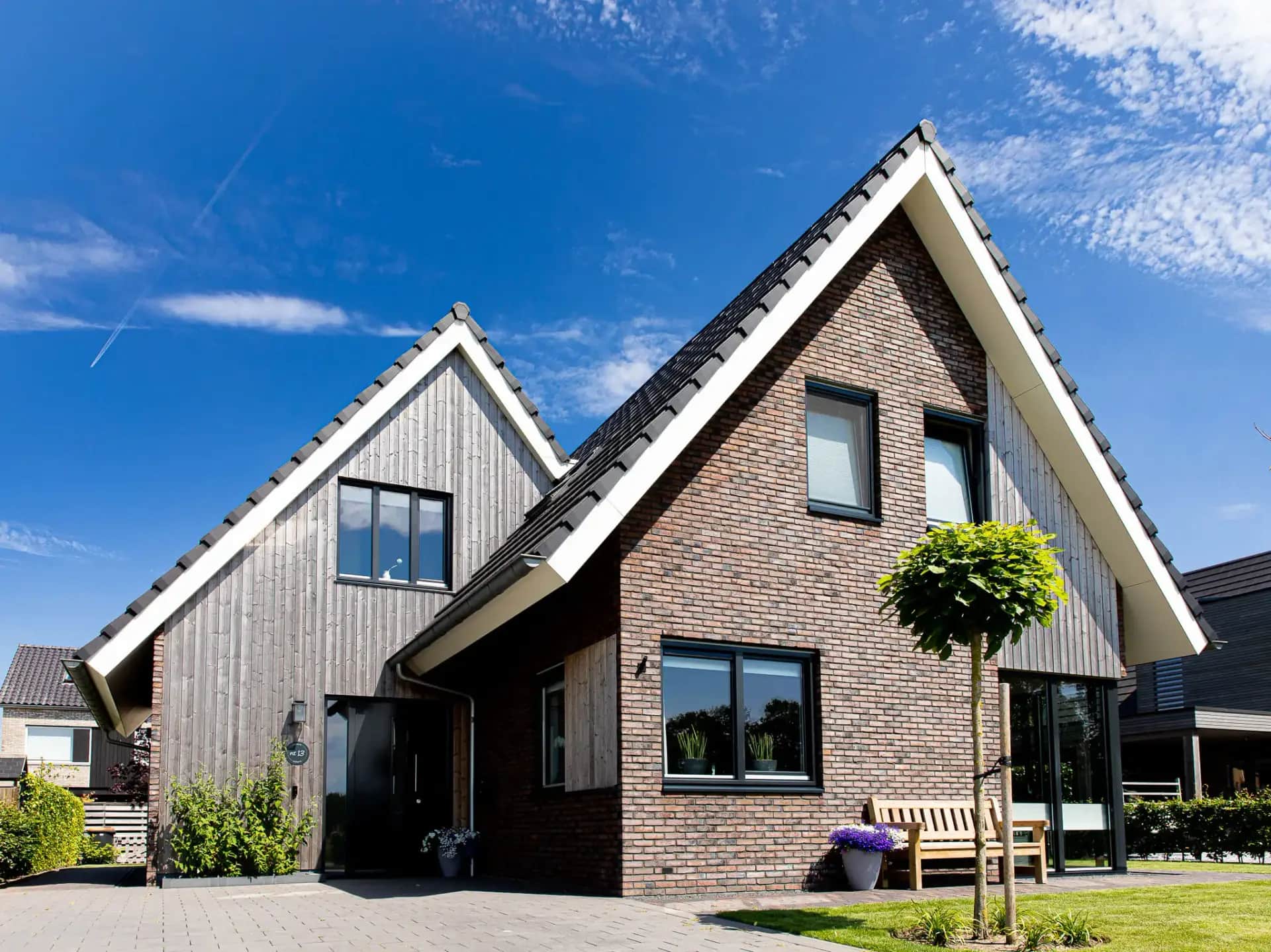 Moderne parallelle kapwoning in Willemsoord met bakstenen gevel, witte afwerkingen en schuine daken tegen blauwe lucht