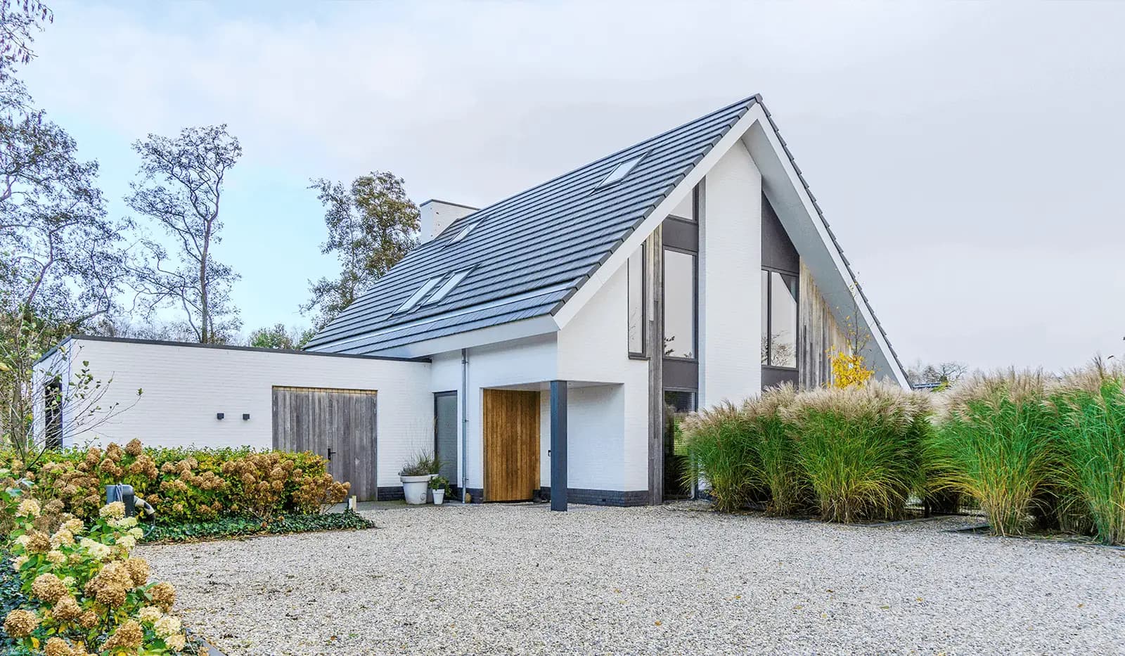 Modern minimalistisch woonhuis in Oranjewoud met verticale gevelelementen, keim-afwerking en grote glaspartijen.