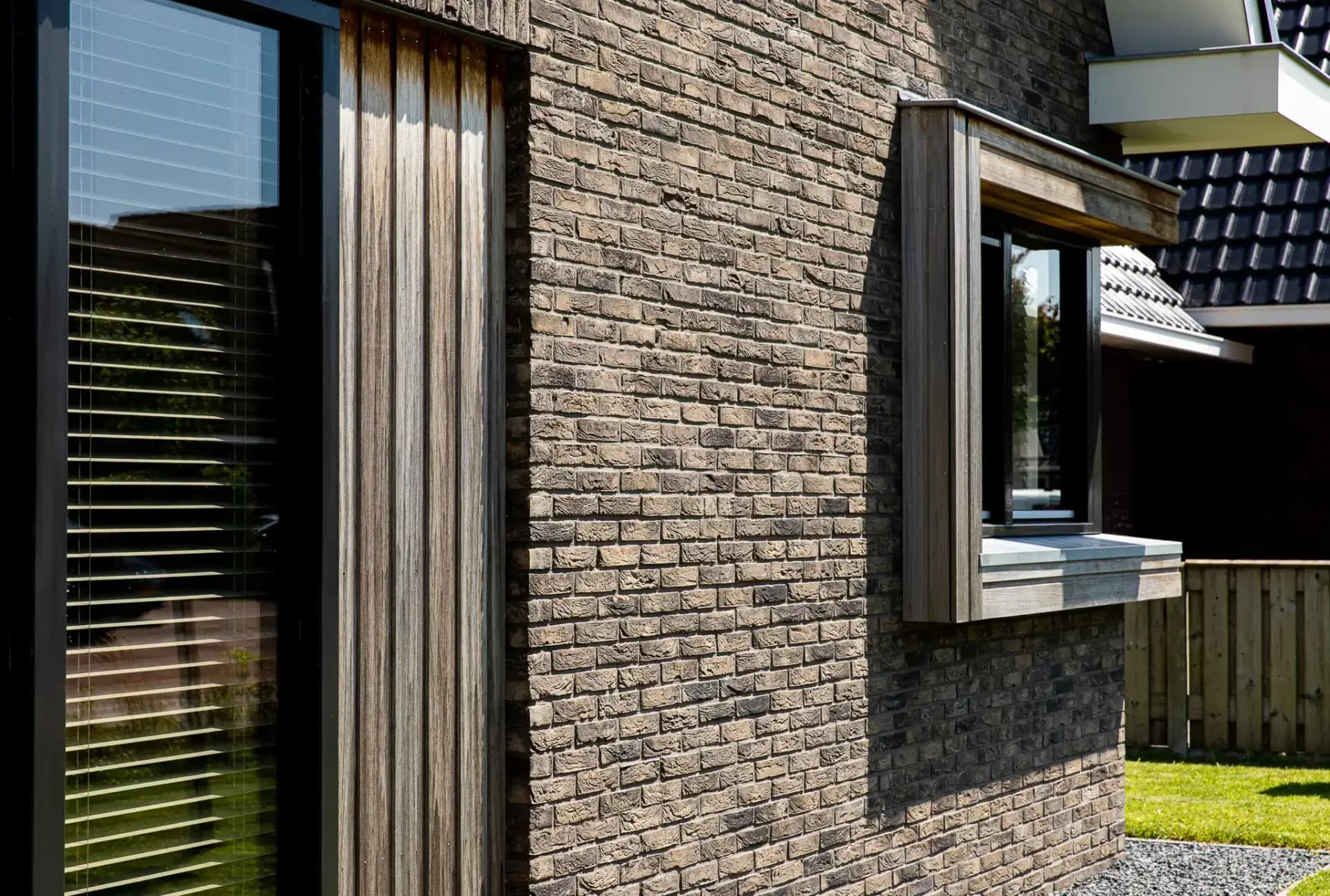 Traditioneel woonhuis Argusvlinder in Wolvega met klassieke gevel, zijbeuk en moderne kleurstelling — grote glaspartijen openen naar uitzicht op het water.